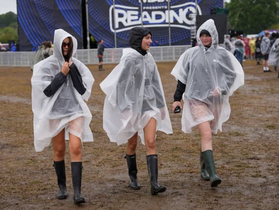 Festivalgoers cover up with plastic ponchos for the heavy rainfall at the Reading Festival at Little John’s Farm, Reading, Berkshire.