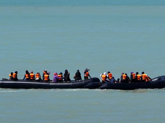 Two small boats hug the coastline near Ault in France in June, as people thought to be migrants are collected along the coastline before an attempt to cross the Channel