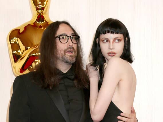 Sean Ono Lennon and Charlotte Kemp Muhl embracing while posing for photos next to a large Oscar statue