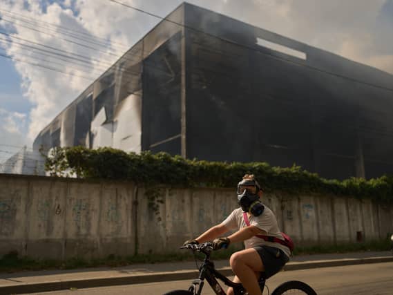 A local resident wears a gas mask as he rides a bicycle past a partially destroyed warehouse after a Russian drone attack in Brovary on the outskirts of Kyiv