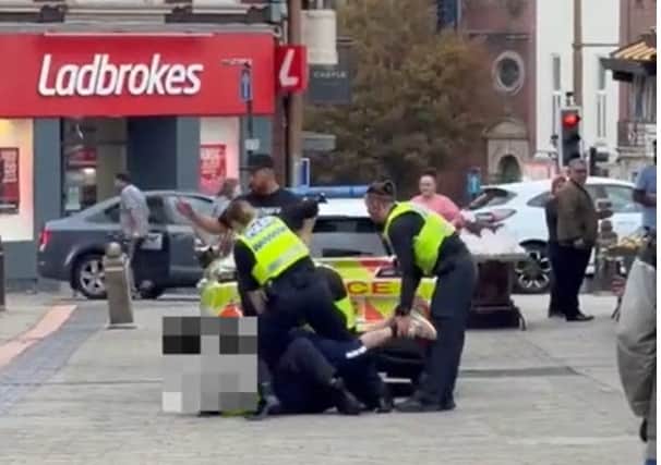 The man (face blurred) was arrested by several police officers