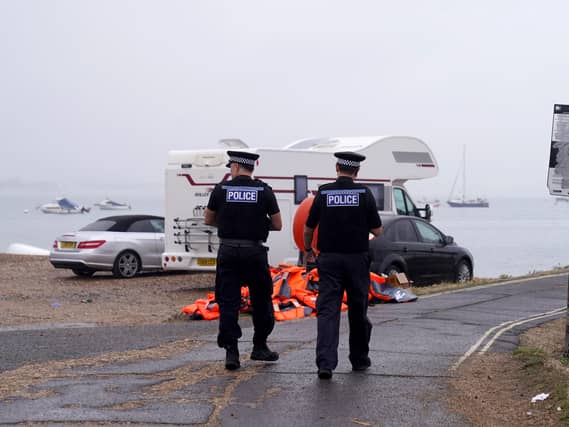 Police officers pass a pile of discarded life jackets