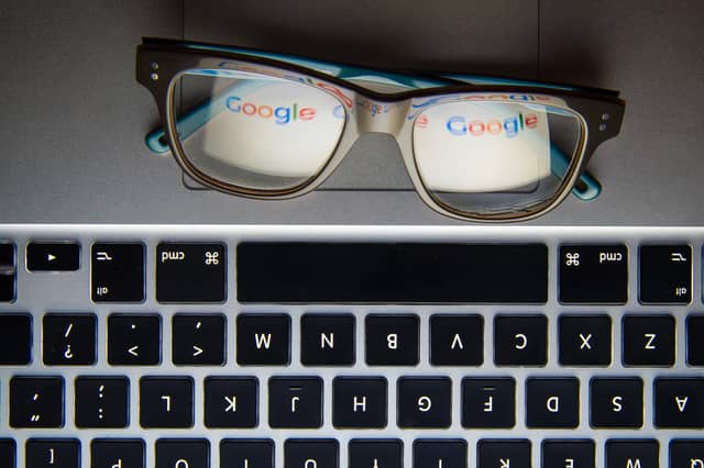 A pair of glasses on a laptop keyboard reflecting the Google logo
