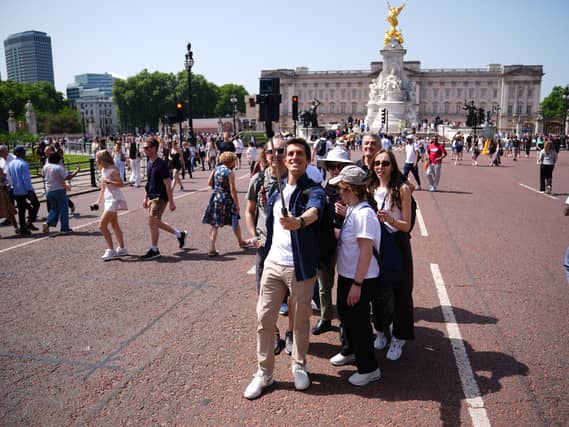 Tourists posing for a selfie in front of Buckingham Palace