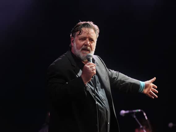 Russell Crowe on stage singing into a microphone