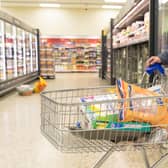 A shopper with a trolley filled with groceries at a supermarket