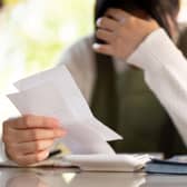 A woman with their hand on their head in distress while reading paperwork
