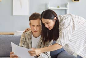 A couple looking at a bill, while on the sofa