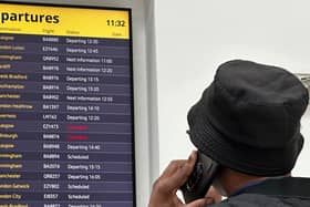 A man uses his mobile phone as he looks at a flight departure board showing cancellations on flights to Scotland, at George Best Belfast City Airport during disruption