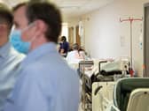 Patients wait on beds in a hospital corridor