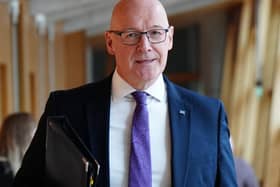 John Swinney smiling in a Holyrood corridor
