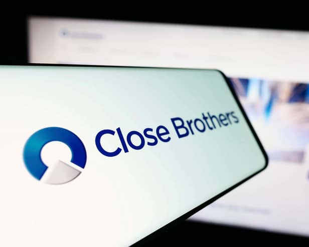 Mobile phone with logo of British merchant bank company Close Brothers Group in front of website