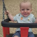 A young boy sitting in a swing and smiling at the camera