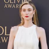 Elizabeth Debicki posing with her hands in front of her wearing a white dress at the Olivier Awards