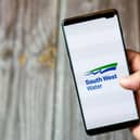 A mobile phone being held by a hand with the South West Water app