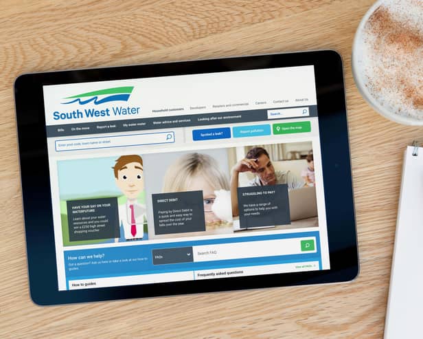 A man looks at the South West Water website on his iPad tablet device, shot against a wooden table top background