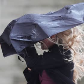 Strong wind blowing an umbrella held by woman