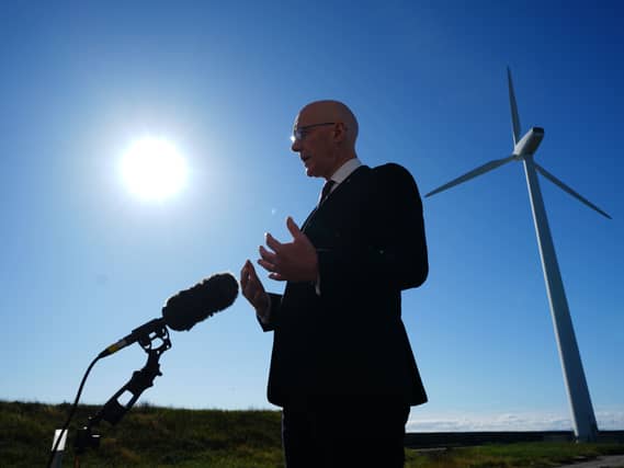 John Swinney standing in front of a wind turbine