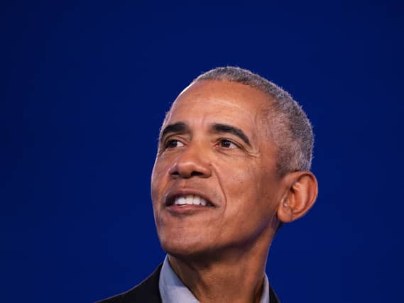 Barack Obama smiling in front of a blue background
