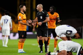 Referee Tim Robinson speaks with Adam Armstrong after showing a yellow card to Mateus Mane