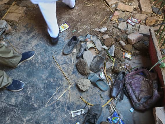 A rescue worker stand beside shoes and a school bag of victim children at the the site of a roof collapse