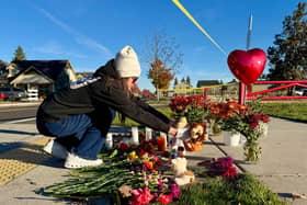 A woman places flowers at a makeshift memorial