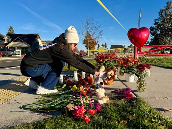A woman places flowers at a makeshift memorial
