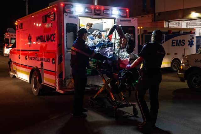Paramedics load an injured person into an ambulance (John Ulan/The Canadian Press via AP)
