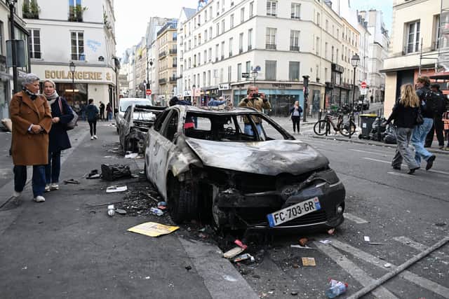 People look at burnt-out cars the day after a demonstration (Emma Da Silva/AP)