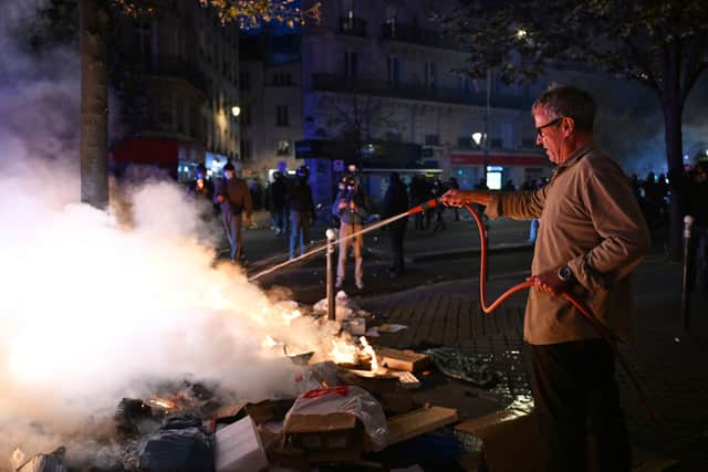 A man tries to extinguish a fire during clashes between protesters and police in Paris (Emma Da Silva/AP)