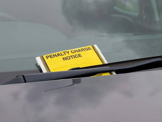 A penalty charge notice parking fine attached to car windscreen