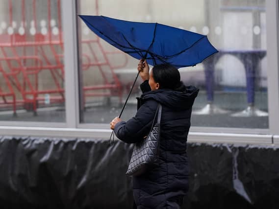 A woman's umbrella blows inside out while she is walking in strong wind