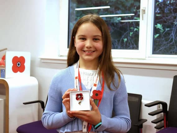 Ava Mitchell smiling, holding up a poppy