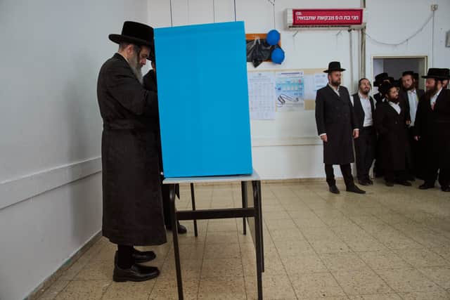 Ultra-Orthodox Jewish men watch their Rabbi Chaim Hager cast his ballot at a polling station (Oded Balilty/AP)