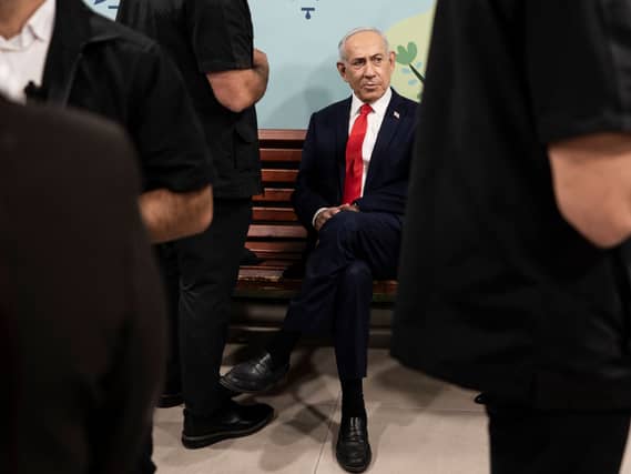 Benjamin Netanyahu sitting down among a crowd of people