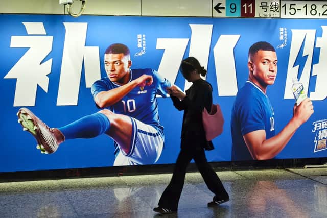 A woman walks by an advertisement featuring Kylian Mbappe in Shanghai, China (Chinatopix Via AP)