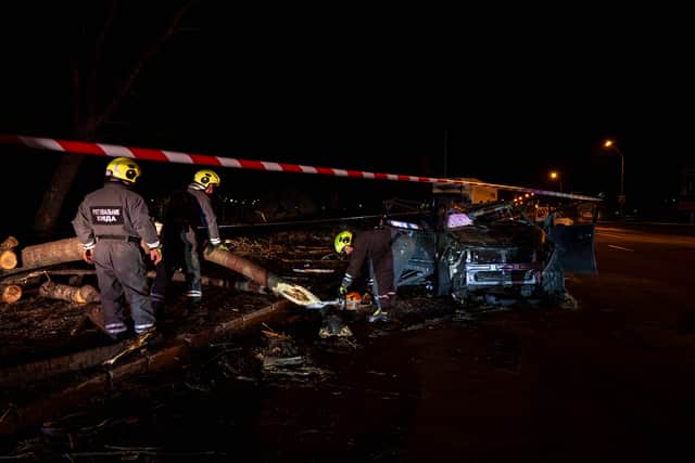 Emergency workers clear debris near a destroyed car following a Russian strike in Kyiv (Dan Bashakov/AP)