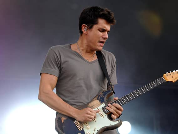 John Mayer playing guitar while performing on stage