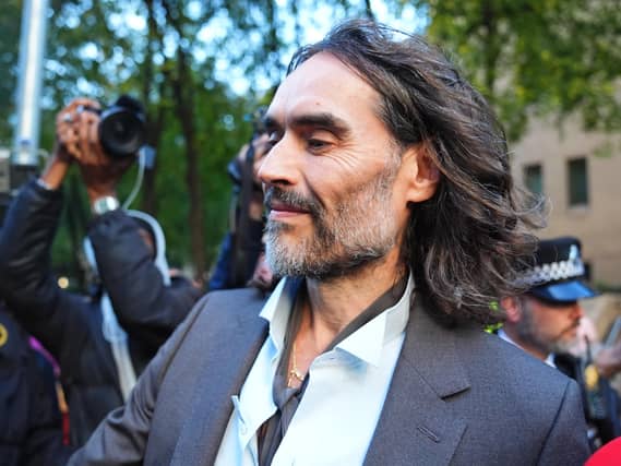 Russell Brand smiling outside court