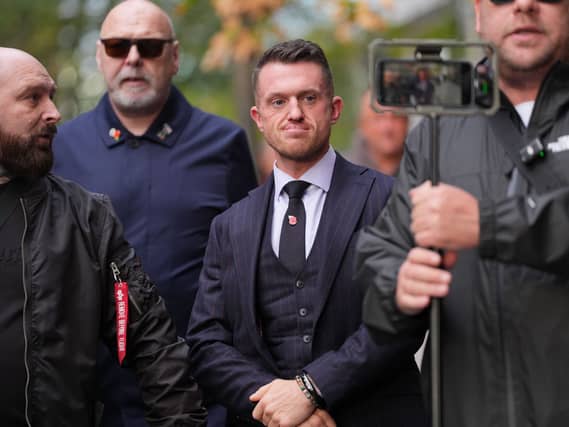 Tommy Robinson surrounded by security and a man filming on a phone