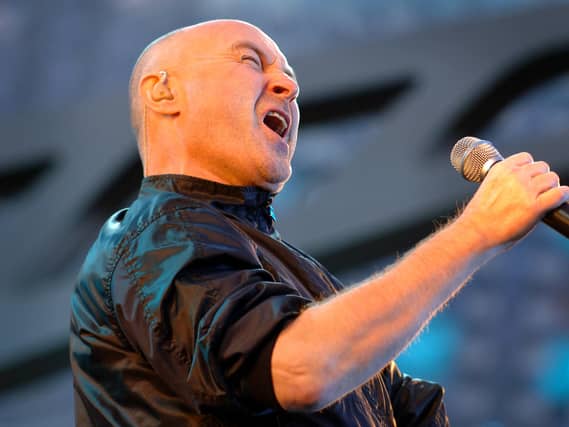 Phil Collins singing into a microphone on stage