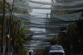 A local man rides a bicycle beneath anti-drone nets stretched over a street during a local ceasefire in Oleshky