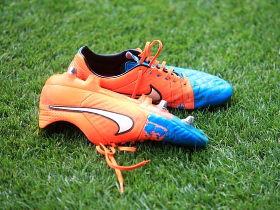 A pair of worn Nike football boots on a pitch
