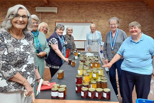 Members eagerly purchasing preserves, with Chairman Chris Ballett, left of Melanie Latham