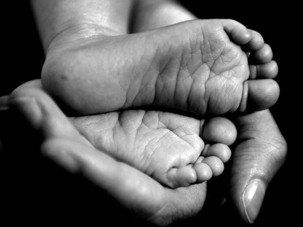 A hand holding a baby's feet