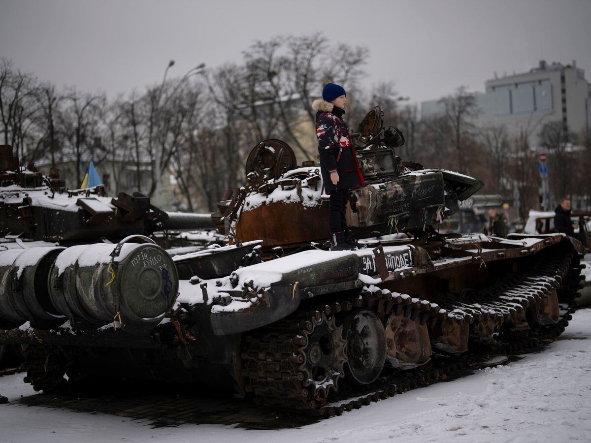 A boy stands on a destroyed Russian tank in Kyiv