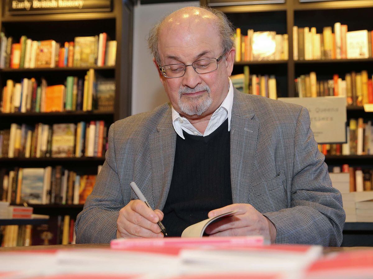 Salman Rushdie signs a book in a bookstore