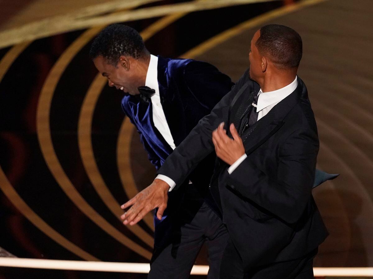 Will Smith, right, hits presenter Chris Rock during the Oscars