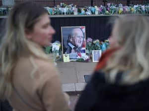 People look at flowers left outside Buckingham Palace, London, following the announcement of the death of the Duke of Edinburgh at the age of 99.