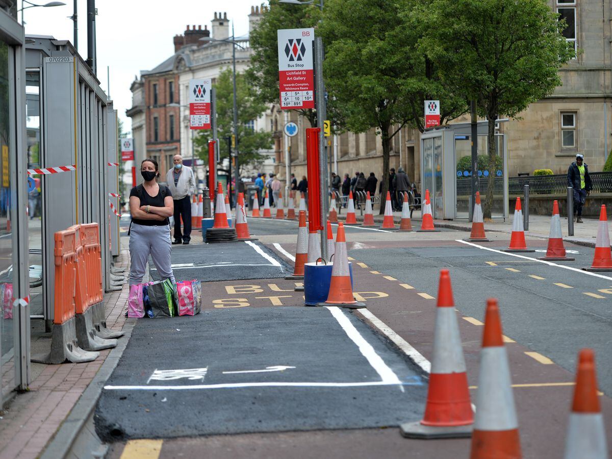 This shopper waits a newly extended bus stop in Wolverhampton as pavements are extended and Lichfield Street is now one-way with a cycle lane